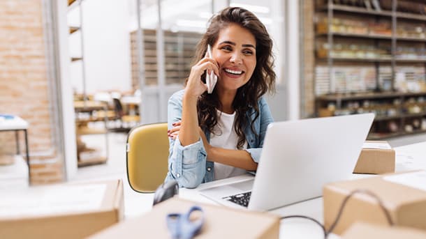 Female sitting down on phone with an open laptop